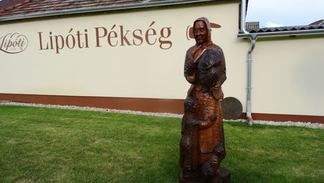 Kenyérszelő asszony gyermekkel, Bálint József fafaragó alkotása, a Lipóti Pékség udvarán 2016. június 13.-án